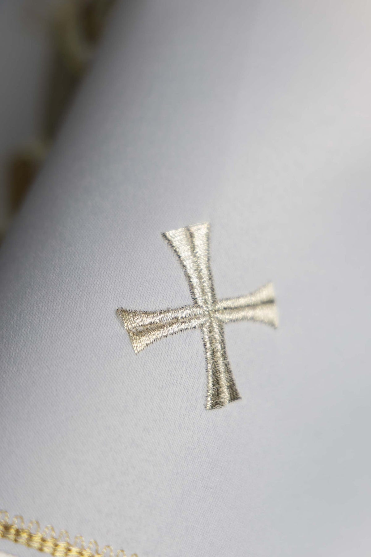 Biały welon na puszkę z haftowanym krzyżem, zbliżenie haftu