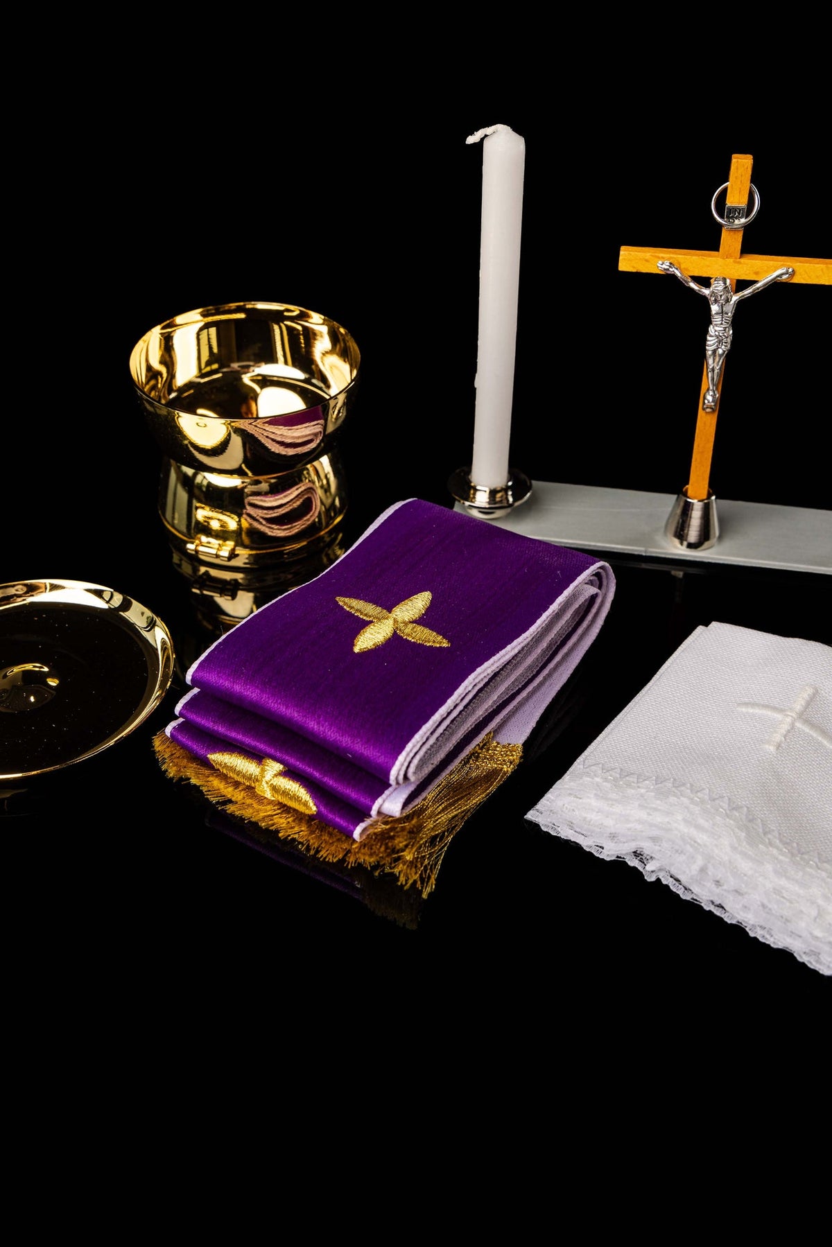 Złote naczynie liturgiczne i biała świeca z zestawu, zbliżenie